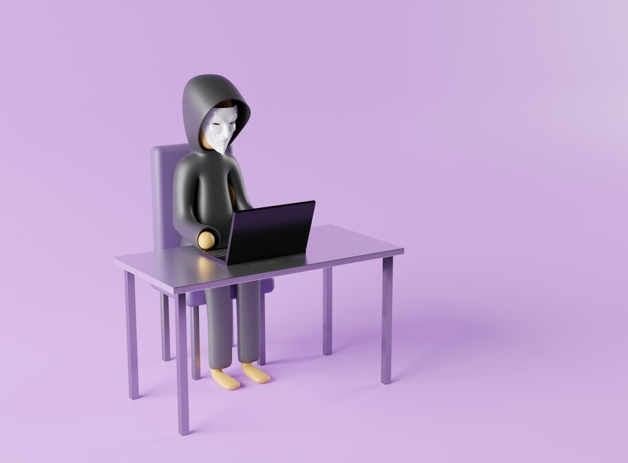 eine Kunststofffigur mit Maske sitzt vor einem Laptop