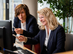 Bettina Pilsel und Sigrid Rulitz freuen sich und blicken in den Bildschirm