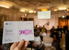 Eine Hand hält das Programm der Veranstaltung zum Thema Klima und im Hintergrund...