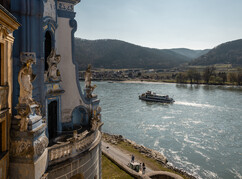 Ein Schiff fährt die Donau auf Höhe von Dürnstein entlang