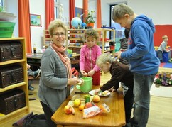 Eine Frau und Kinder schälen gemeinsam Äpfel